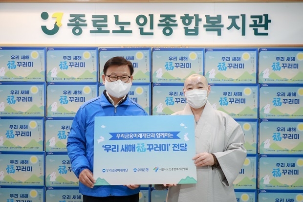 우리은행이 20일 종로노인종합복지관에 '우리 새해 복 꾸러미' 를 전달했다. 이원덕 우리은행장과 정관 관장이 기념사진을 촬영하고 있다. ⓒ타임즈