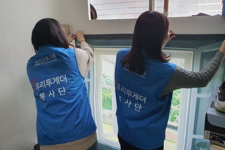 우리금융미래재단 직원들이 쪽방촌 주민들을 위해 방한커튼을 설치하고 있다. ⓒ타임즈