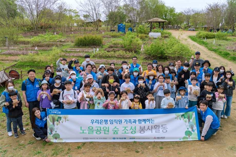 우리은행, 임직원 가족 참여 노을공원 숲 조성 봉사홀동 실시_1 ⓒ타임즈<br>
■ 사진설명1 : 우리은행(은행장 이원덕)은 지난 23일 마포구 상암동 소재 노을공원에서 숲 조성 봉사활동을 실시했다. 참여한 임직원 및 가족들이 묘목을 들고 기념촬영을 하고 있다.
