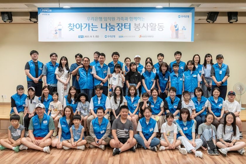 지난 5일 서울 중구 중림동 중림종합사회복지관 강당에서 '찾아가는 나눔장터' 봉사활동에 참여한 우리은행 임직원과 가족들이 단체사진 촬영을 하고 있다. ⓒ타임즈