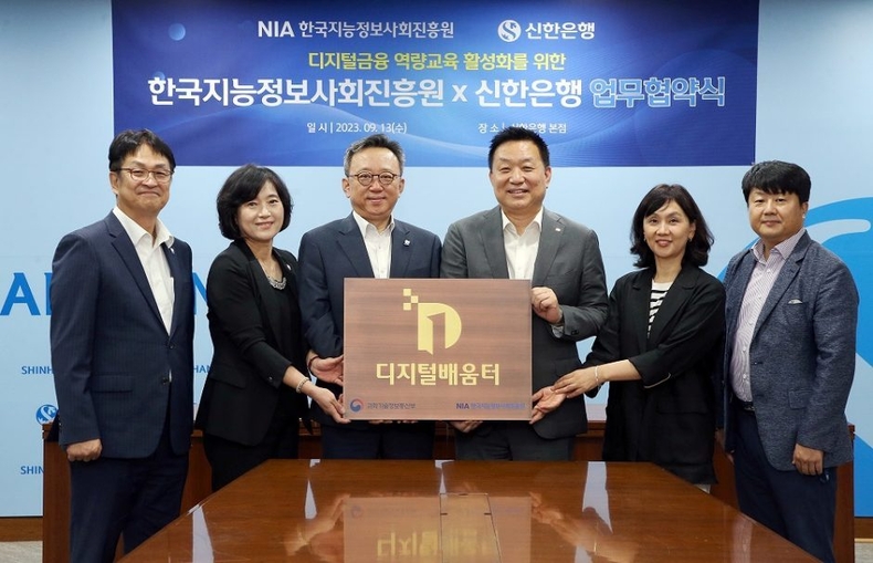 신한은행 한국지능정보사회진흥원 업무협약 사진 2 ⓒ타임즈<br>
사진설명2) 서울시 중구 소재 신한은행 본점에서 진행된 디지털금융 역량교육 활성화를 위한 업무협약식에서 신한은행 정상혁 은행장(왼쪽에서 세번째), 한국지능정보사회진흥원 황종성 원장(왼쪽에서 네번째) 및 관계자들이 ‘디지털배움터’ 현판 전달식을 기념하는 모습