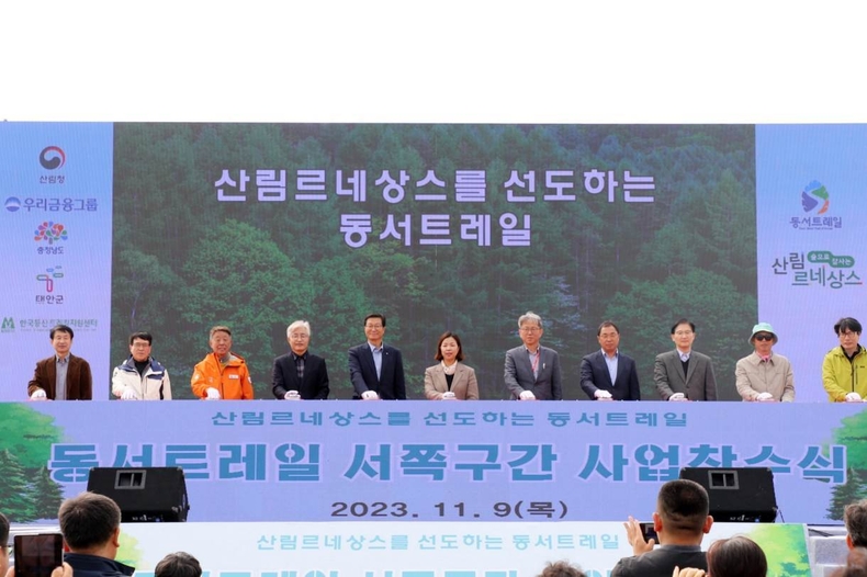 우리금융, 동서트레일 안면도 구간 조성사업 참여_1 ⓒ타임즈<br>
■ 사진설명1 : 우리금융그룹(회장 임종룡)은 9일 충청남도 태안군 안면읍에서 열린 ‘동서트레일 서쪽 첫 구간 사업’ 착수식에 참여했다. 한국등산트레킹지원센터 전범권 이사장(왼쪽 4번째), 우리금융그룹 미래사업추진부문 김건호 상무(왼쪽 5번째), 산림청 산림복지국 강혜영 국장(왼쪽 6번째), 충청남도 농림축산국 오진기 국장(오른쪽 5번째), 태안군 박경찬 부군수(오른쪽 4번째)가 기념촬영을 하고 있다.