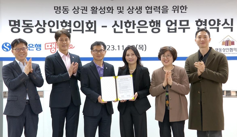 (보도자료이미지1)신한은행, 지역상권과 상생금융을 위한 따뜻한 동행 ⓒ타임즈<br>
사진설명1) 지난 23일 서울시 중구에 위치한 신한은행 명동기업금융센터에서 진행된 ‘명동상인협의회-신한은행 업무협약식’에서 신한은행 중부본부 구춘서 본부장(왼쪽 세번째)과 명동상인협의회 강태은 회장(왼쪽 네번째)이 관계자들과 기념촬영하는 모습.