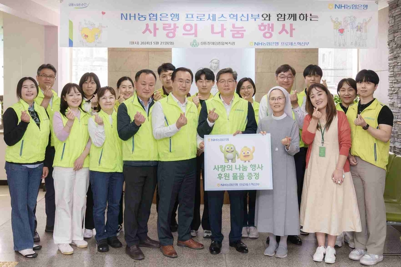 사진설명 : NH농협은행은 21일 서울 성동구 소재 성동장애인복지관을 방문해 후원물품 전달 및 봉사활동을 실시했다. 최성자 성동장애인종합복지관 관장(푯말 든 오른쪽)과 정재호 디지털전략사업부문 부행장(푯말 든 왼쪽) 및 농협은행 프로세스혁신부 직원들이 기념사진을 촬영하고 있다 ⓒ타임즈