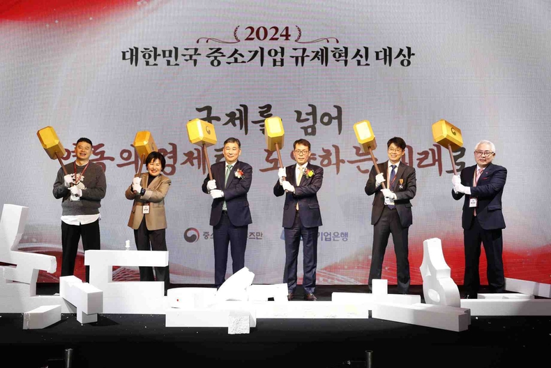 <사진은 16일 서울시 중구 더플라자호텔에서 열린 ‘2024 대한민국 중소기업 규제혁신대상’' 시상식에서 김성태 IBK기업은행장(오른쪽 세번째), 최승재 옴부즈만(왼쪽 세번째) 및 수상자들이 '낡은 규제 장벽'을 망치로 부수는 퍼포먼스를 진행하고 있는 모습>