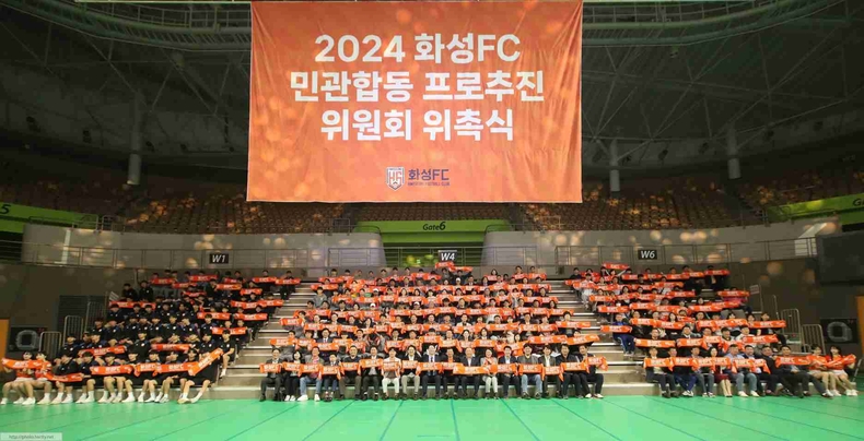 1-2 2024 화성FC 민관합동 프로추진 위원회 위촉식에서 위촉된 위원들이 화성FC 기념수건을 들어올리는 퍼포먼스를 하고 있다