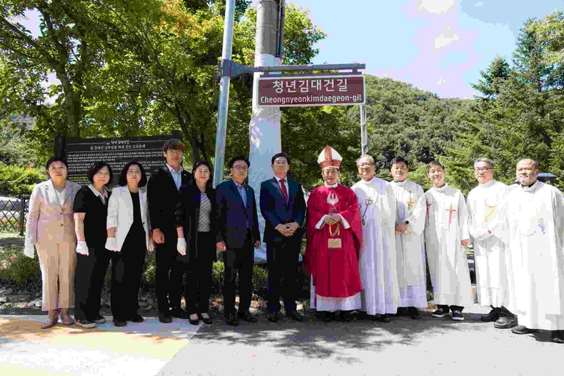 (사진2) 용인특례시의회 의원연구단체 용인, 역사종교문화 여행의 시작2 소속 의원들이 11일 청년 김대건 길 명예도로 현판 아래에서 이상일 용인특례시장, 문희종 주교, 수원교구 소속 신부님 등 사제들과 기념 촬영을 하고 있다. ⓒ타임즈