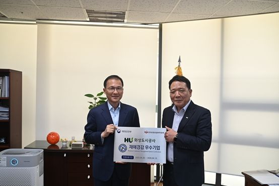인증 현판을 들고 있는 김근영 HU공사 사장(좌), 장경의 HU공사 감사실장(우)