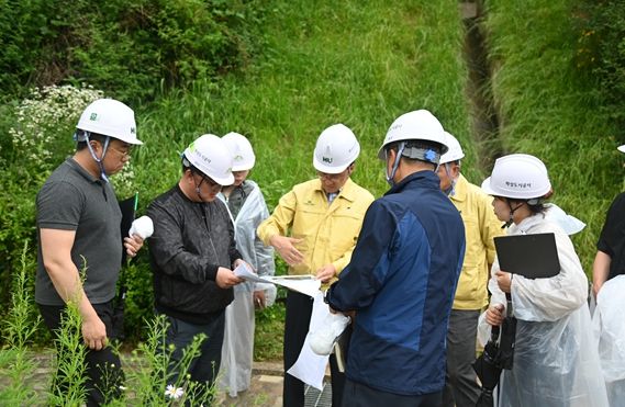 화성 함백산추모공원에서 김근영 사장(가운데 노란옷)과 안전관리 부서 임직원들이 배수로 설계도면을 확인하며 강우 피해 방지 대책을 세우고 있다.(화성도시공사 제공)