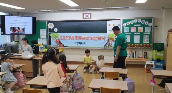 일산초등학교 1학년 아동이 훈련사의 지도 아래 훈련견을 만져보고 있다.