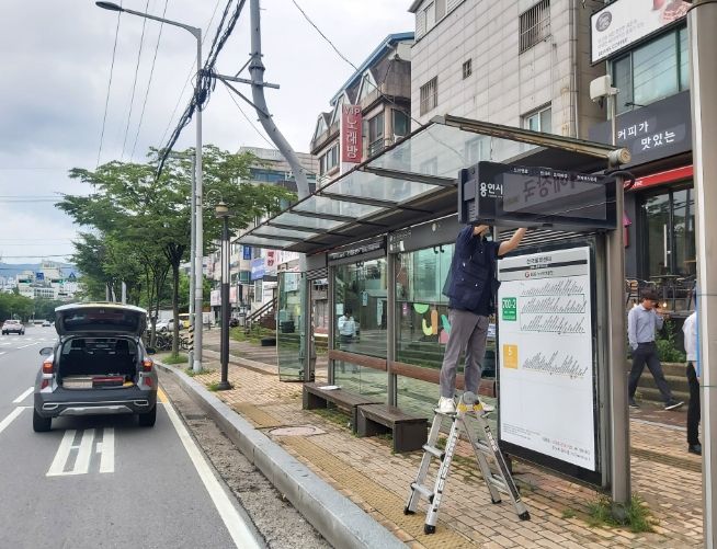 시 관계자가 스안내전광판이 없는 정류소에 기기를 설치하고 있다