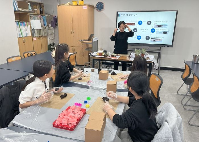 원데이클래스 강사와 참여 청소년들이 커피박 점토를 활용해 나만의 작품을 만들고 자신만의 스타일로 커피박 화분을 꾸미고 있다.